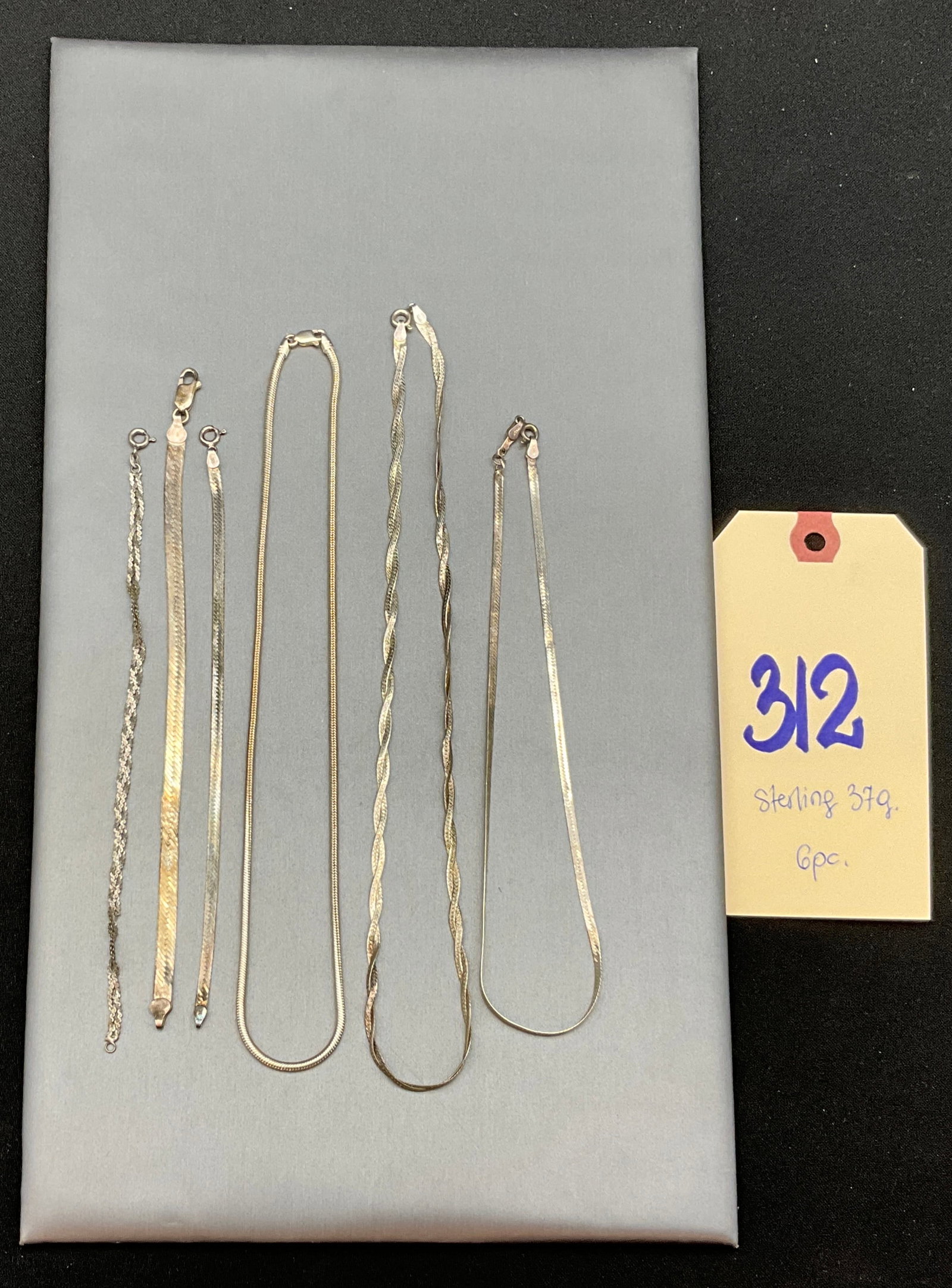Six Vintage Italian Sterling Silver Necklaces and Bracelets: This lot consists of six sterling silver jewelry items featuring flat herringbone, round snake, and twisted multi-strand chain designs secured by lobster claw or spring ring clasps. Purity and origin