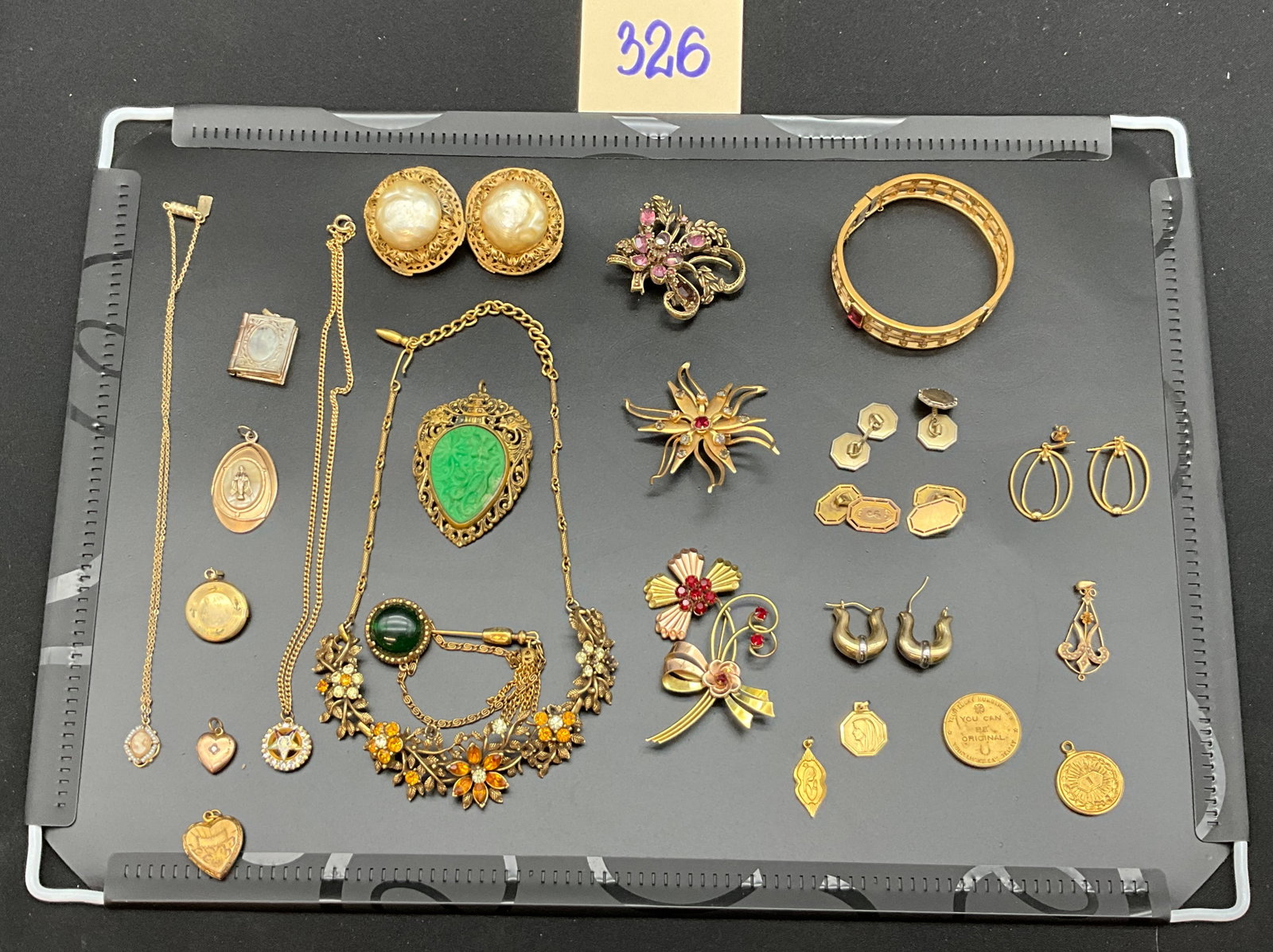 A Collection of Vintage Gold Tone Costume Jewelry: This collection consists of gold-tone necklaces, pendants, lockets, brooches, earrings, and novelty items featuring faceted rhinestones, faux pearls, and a carved green stone. One floral brooch is