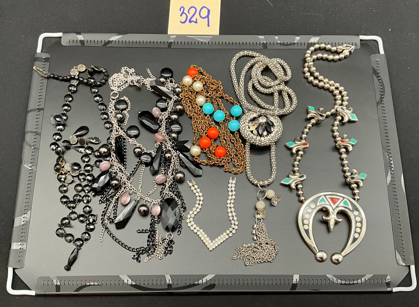 An Assortment of Vintage and Contemporary Costume Jewelry Necklaces: This lot consists of six diverse costume jewelry necklaces including a large enameled horseshoe pendant with fleur-de-lis links and a silver-tone mesh tassel necklace. The collection features a