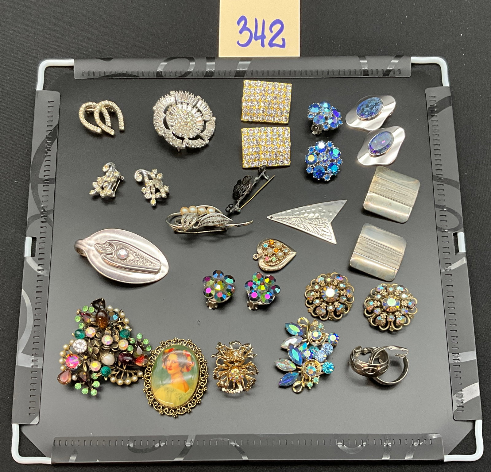 A Collection of Pieces of Vintage Costume Jewelry: This collection features an assortment of vintage brooches, clip-on earrings, and pendants in gold-tone and silver-tone metal decorated with rhinestones and faux pearls. One pendant is fashioned from 