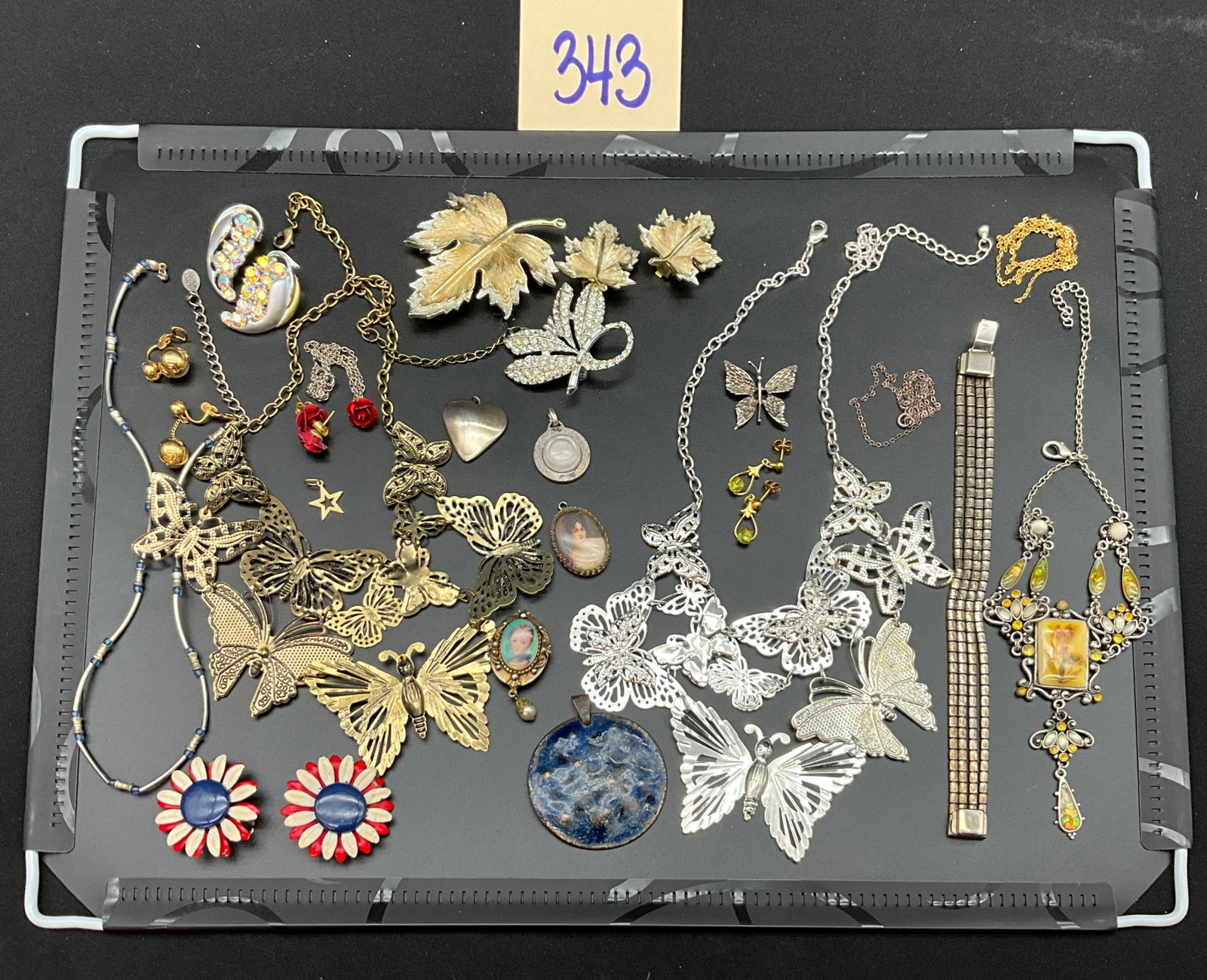 Vintage Butterfly and Botanical Theme Costume Jewelry Collection: This collection features an assortment of necklaces, brooches, and earrings executed in silver, gold, and brass tones with prominent butterfly and botanical motifs. Decorative elements include filigre