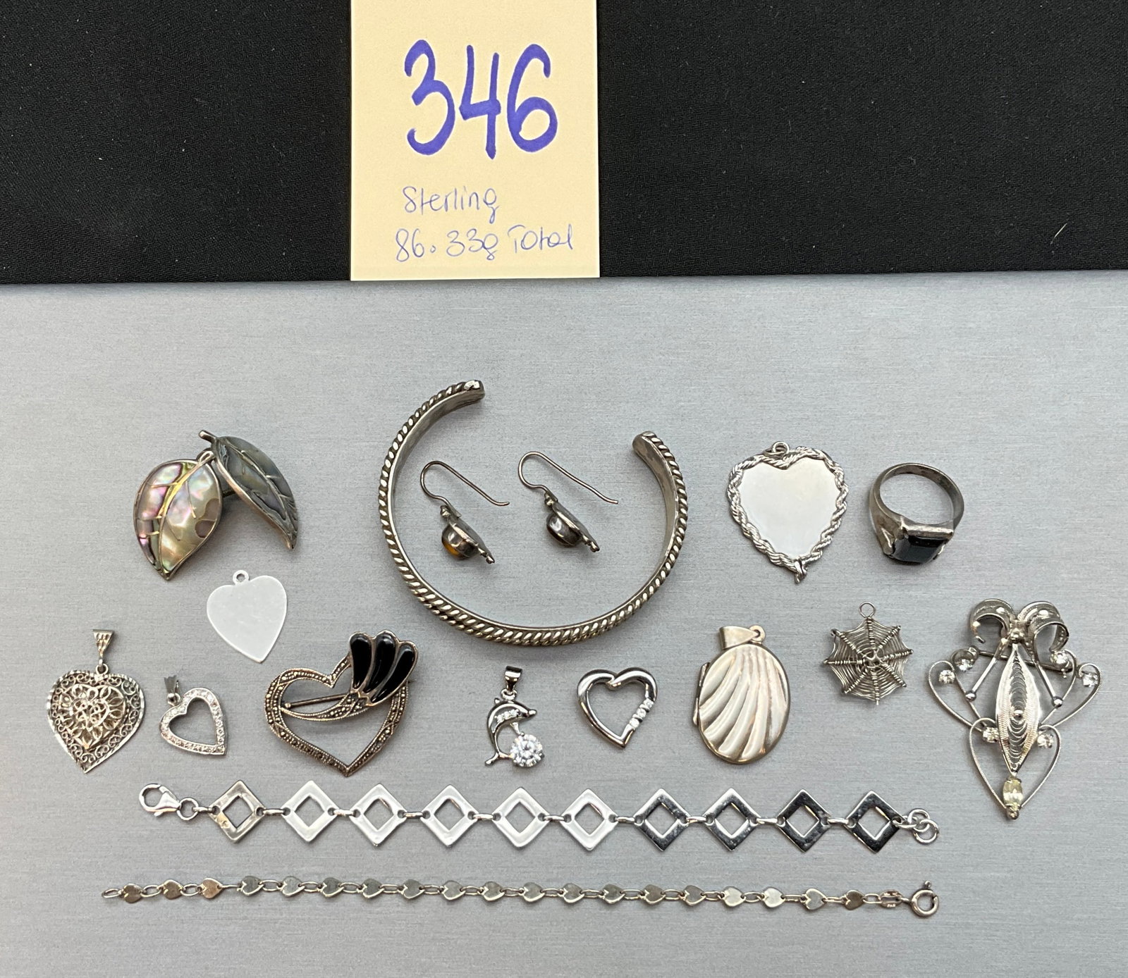 A Collection of Vintage Sterling Silver Jewelry: This lot consists of an assortment of silver jewelry including multiple brooches, bracelets, earrings, a ring, and various pendants featuring mother-of-pearl, tiger eye, and faceted clear stones. The 