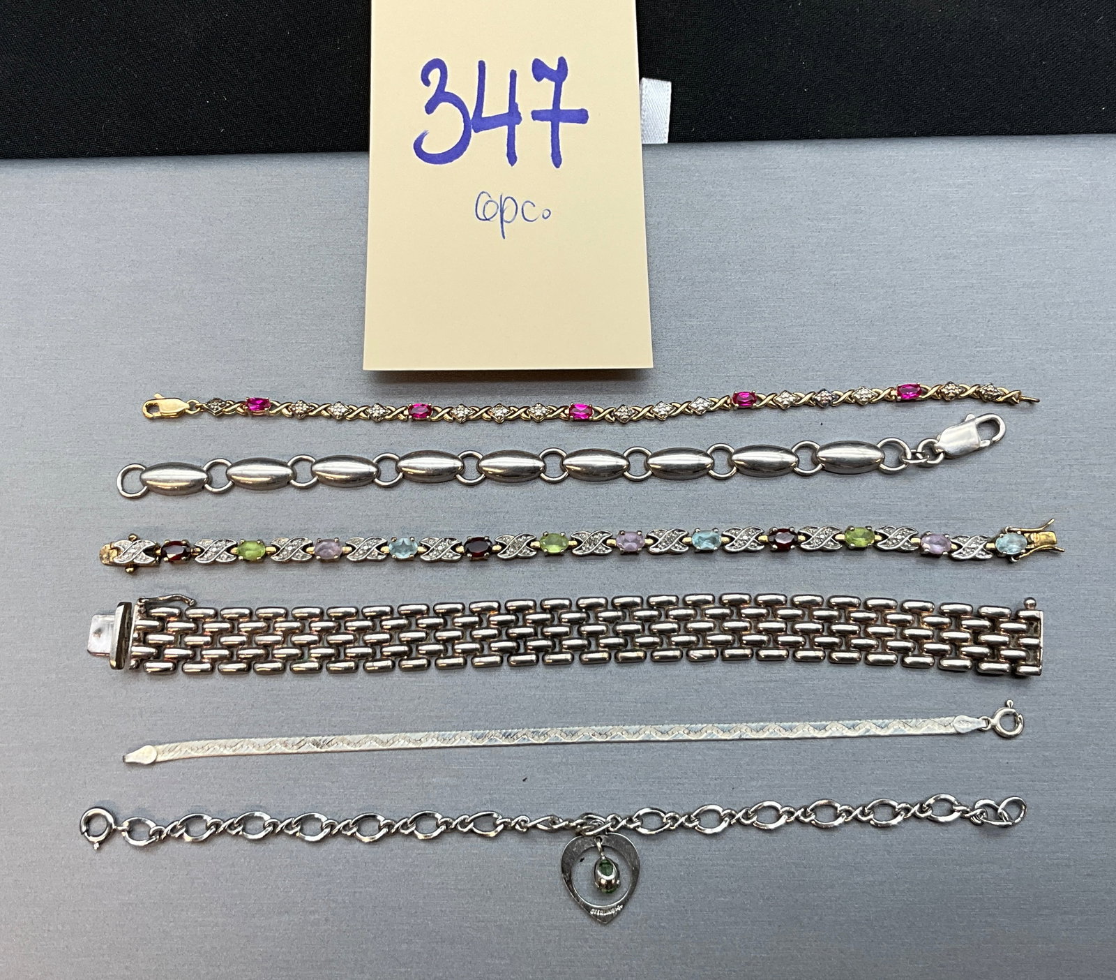 A Collection of Vintage Sterling Silver and Multi-Gemstone Bracelets: This collection of vintage sterling silver and gold-tone bracelets features a variety of designs including tennis, wide panther-link, puffed oval link, flat herringbone, and charm styles. Several piec