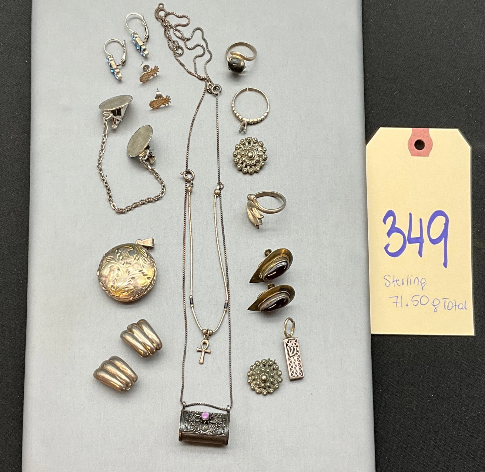 A Collection of Vintage Sterling Silver Jewelry: This collection of vintage sterling silver jewelry features an assortment of items including a foliate engraved locket, a prayer box pendant, and necklaces with ankh and Hebrew letter motifs. The grou