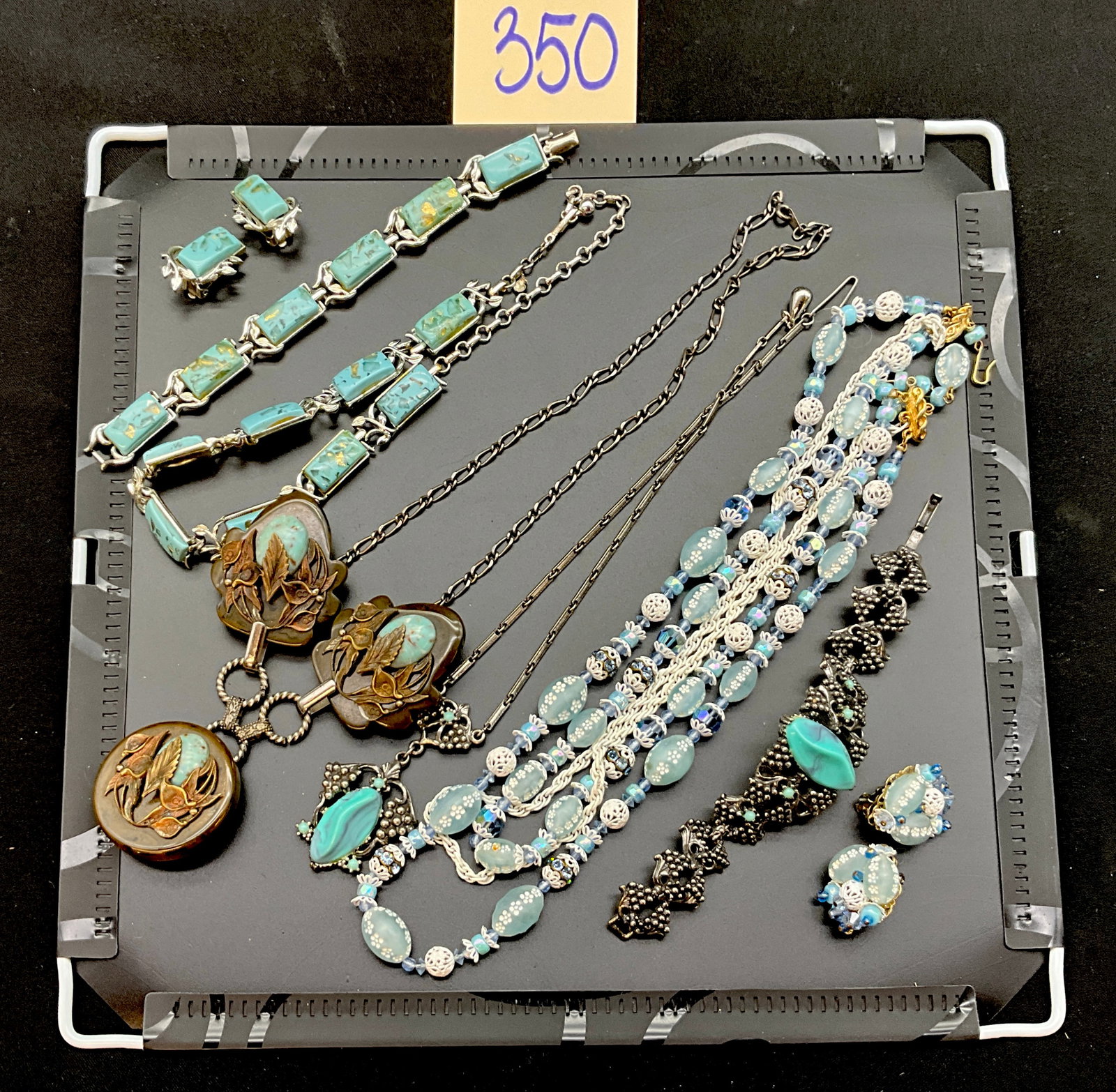 A Collection of Vintage Mid-Century Modern Costume Jewelry: This collection features an assortment of vintage mid-century modern costume jewelry in turquoise and blue tones, including necklaces, bracelets, and earrings. The lot includes a multi-strand beaded n