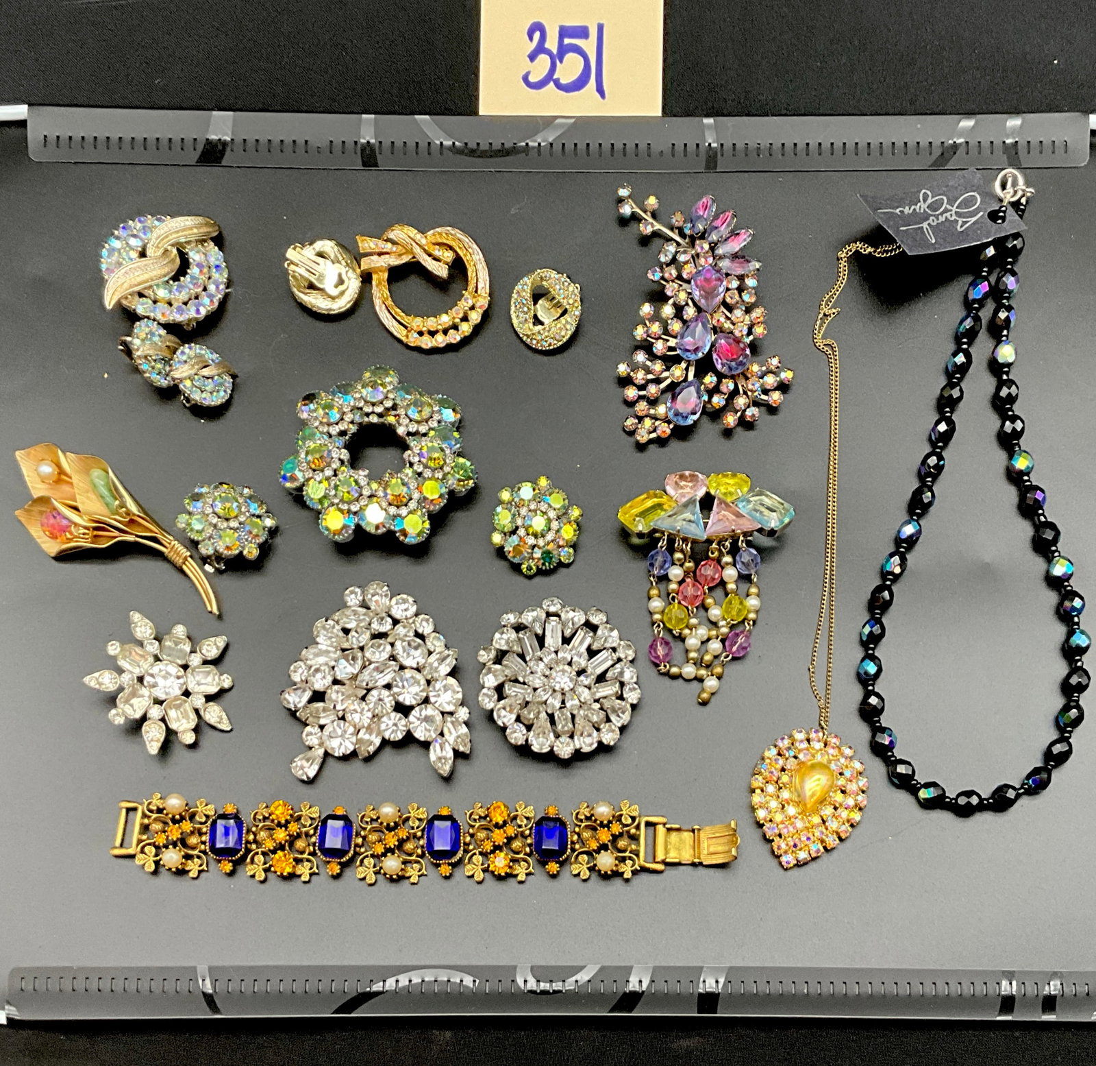 Vintage Mid-Century Style Rhinestone and Glass Costume Jewelry Collection: This collection features a variety of mid-century style costume jewelry including brooches, clip-on earrings, a link bracelet, and necklaces. The pieces are constructed from gold-tone and silver-tone 