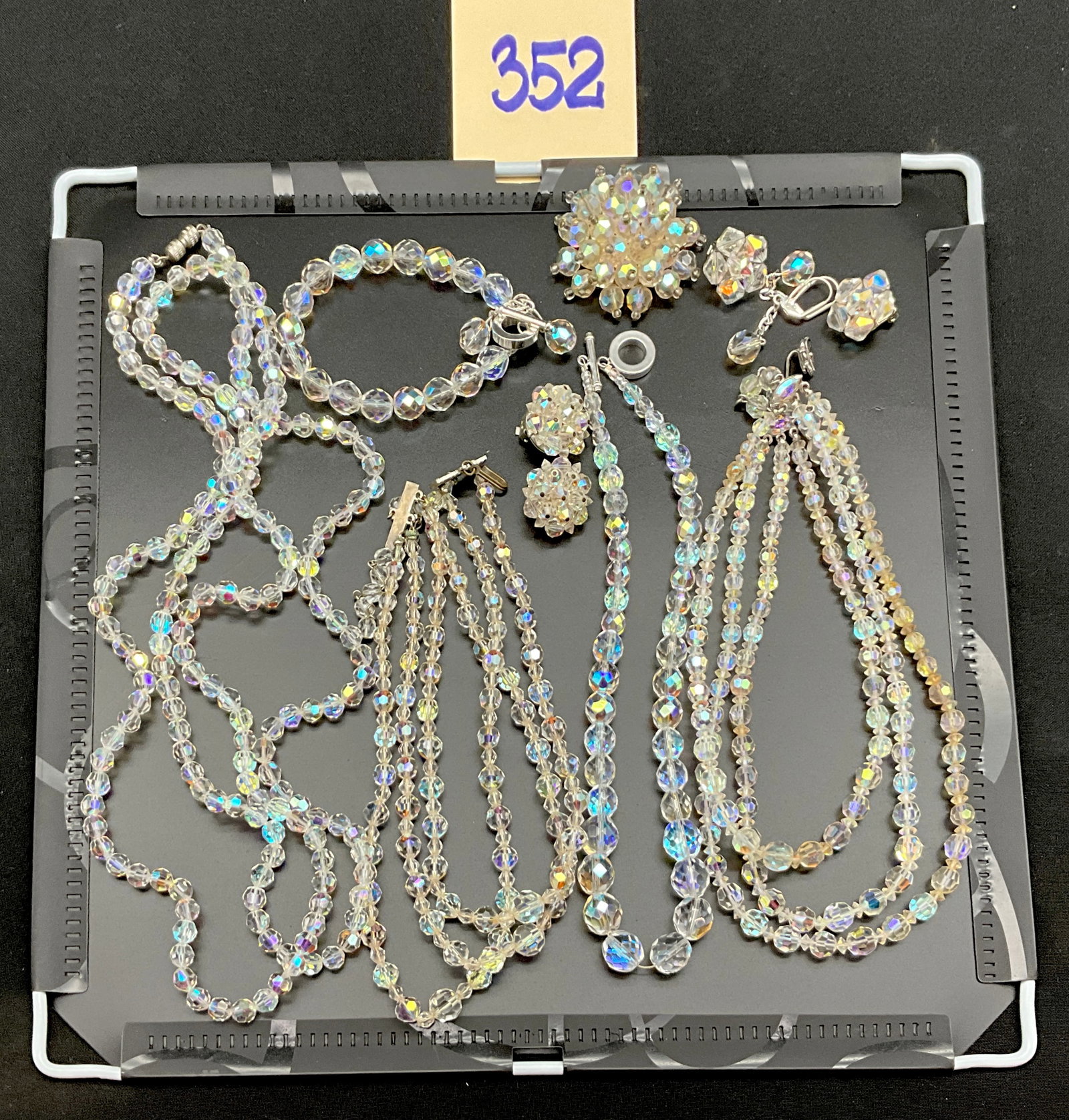 A Collection of Vintage Aurora Borealis Crystal Jewelry: This vintage collection features an assortment of faceted glass jewelry with an iridescent Aurora Borealis coating and silver-tone metal findings, including multiple necklaces, a bracelet, a brooch,
