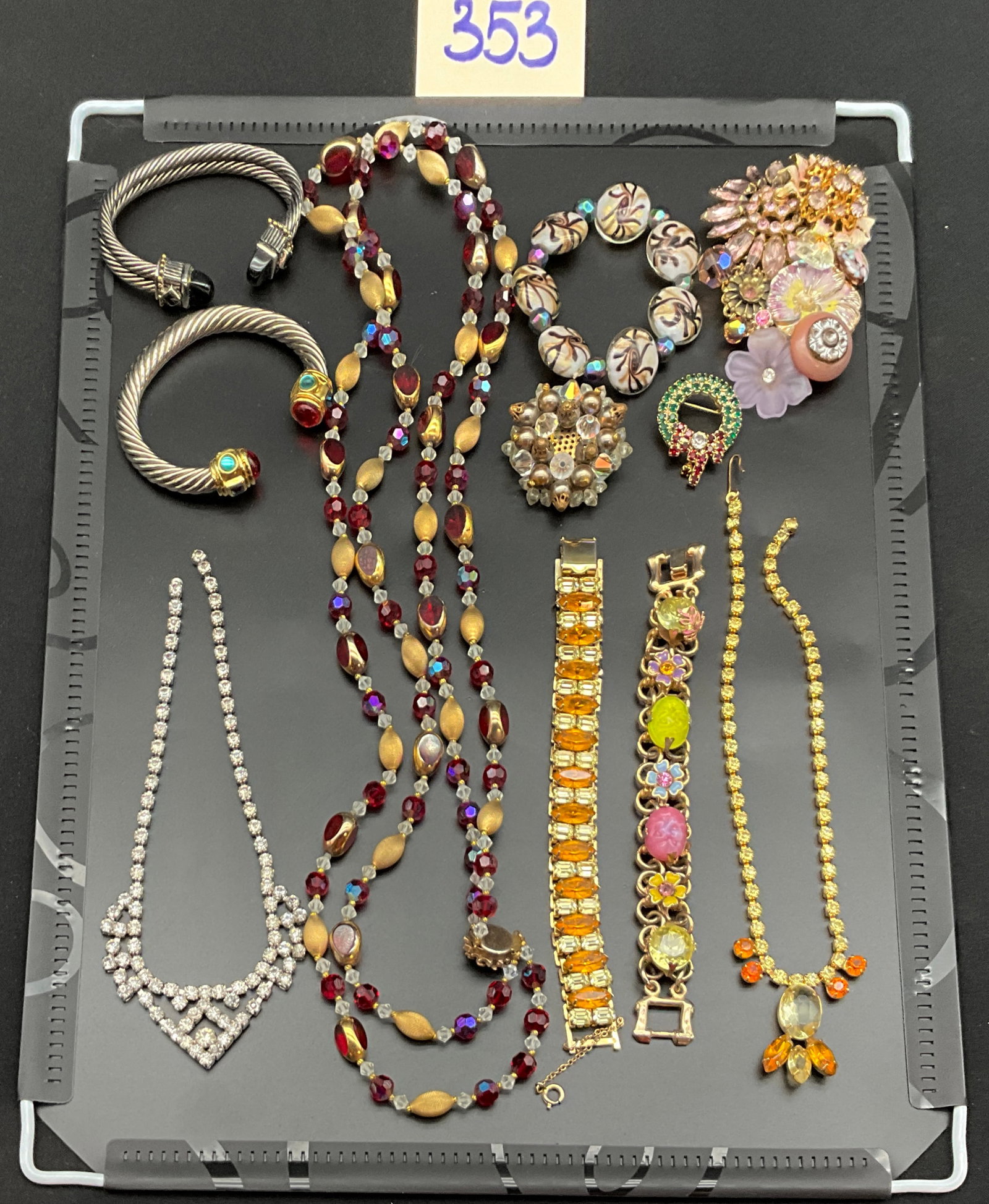 A Collection of Vintage Costume Jewelry: This collection of vintage costume jewelry features an assortment of mid-century necklaces, bracelets, and brooches set with rhinestones, art glass, and molded plastic components. One gold-tone link b