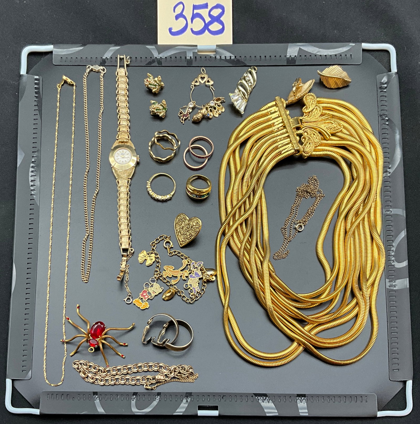 A Collection of Vintage Gold Tone Costume Jewelry and Coro Wristwatch: This collection features a variety of gold-tone and silver costume pieces including a multi-strand gaspipe necklace, a Disney charm bracelet, and a Coro wristwatch. Notable items include a large