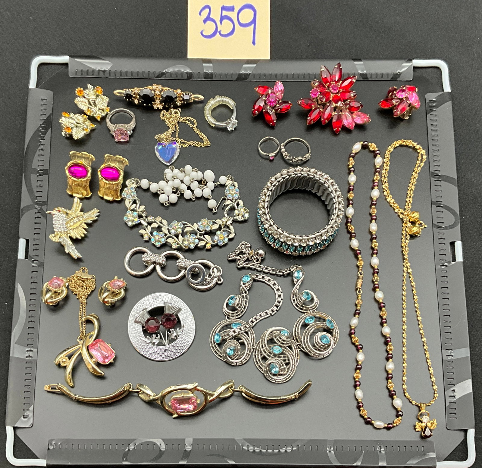 A Collection of Vintage Mid-Century Style Costume Jewelry: This collection features an assortment of vintage costume jewelry including brooches, necklaces, and matching sets decorated with glass rhinestones, faux pearls, and molded glass beads. A circular