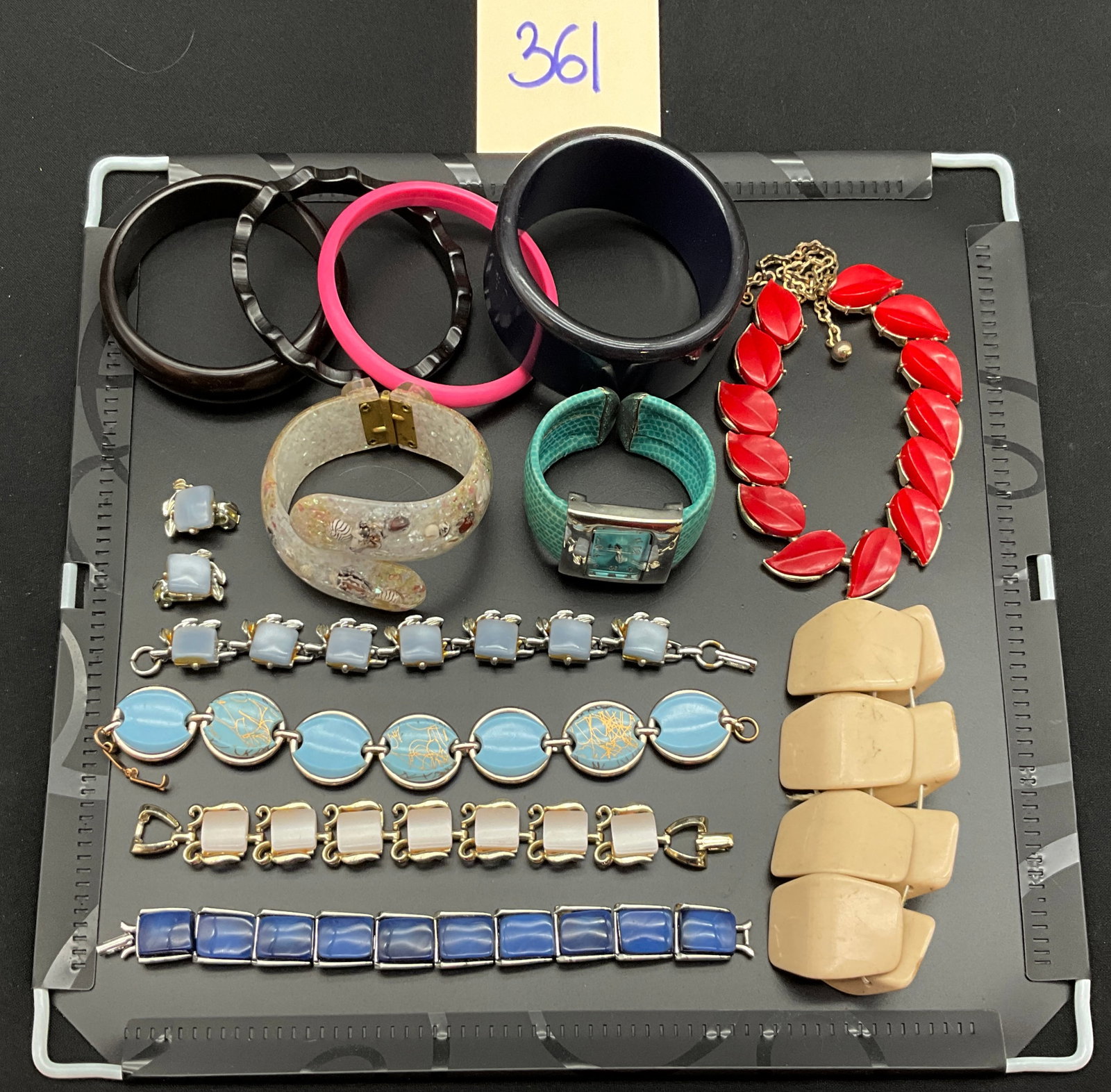 A Collection of Vintage Mid-Century Costume Jewelry: This collection features fourteen pieces of mid-century costume jewelry including a clear Lucite bypass cuff with embedded shells and a turquoise faux-reptile skin watch. The group contains a red