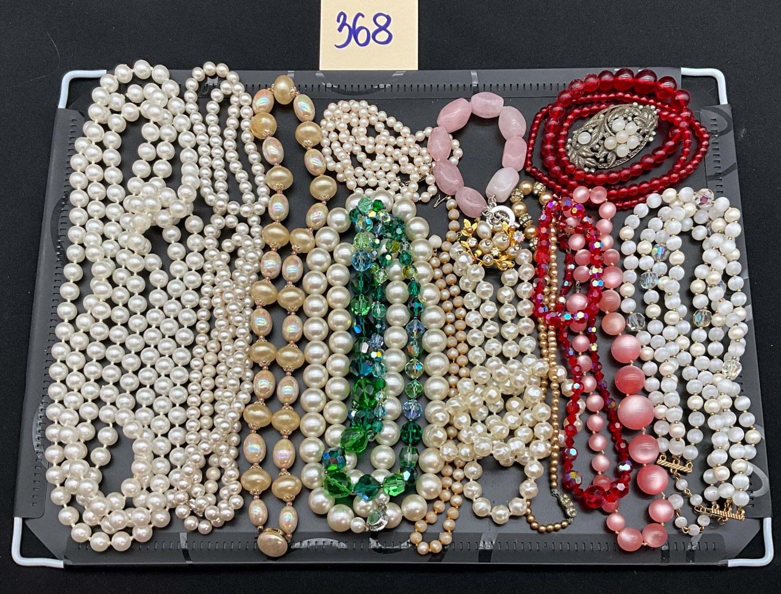 A Collection of Vintage Mid-Century Style Costume Jewelry: This collection of vintage costume jewelry features an assortment of beaded necklaces, brooches, and a bracelet. The pieces are crafted with faux pearls in various shades, faceted glass beads with