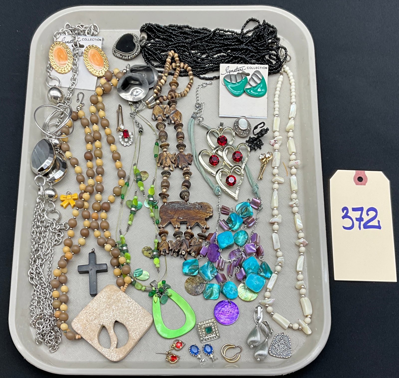 A Collection of Vintage Bohemian and Modernist Costume Jewelry: This collection features an assortment of necklaces, earrings, and pendants crafted from materials including carved wood, dyed mother-of-pearl shell, base metals, and glass beads. The lot includes a