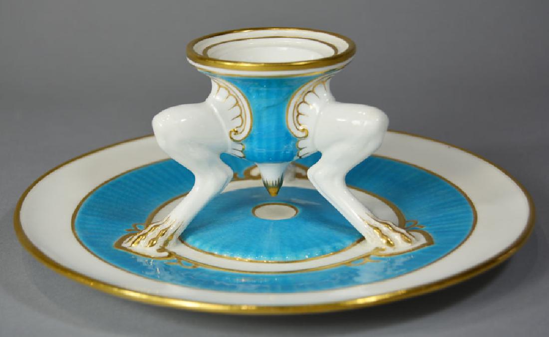 Early 20th C. Mintons Egg Holder: a circular candleholder raised on three animal form legs terminating in paw feet, on a circular base, blue and white china with gilt highlights, 7 3/4" dia., 3 1/4" high.