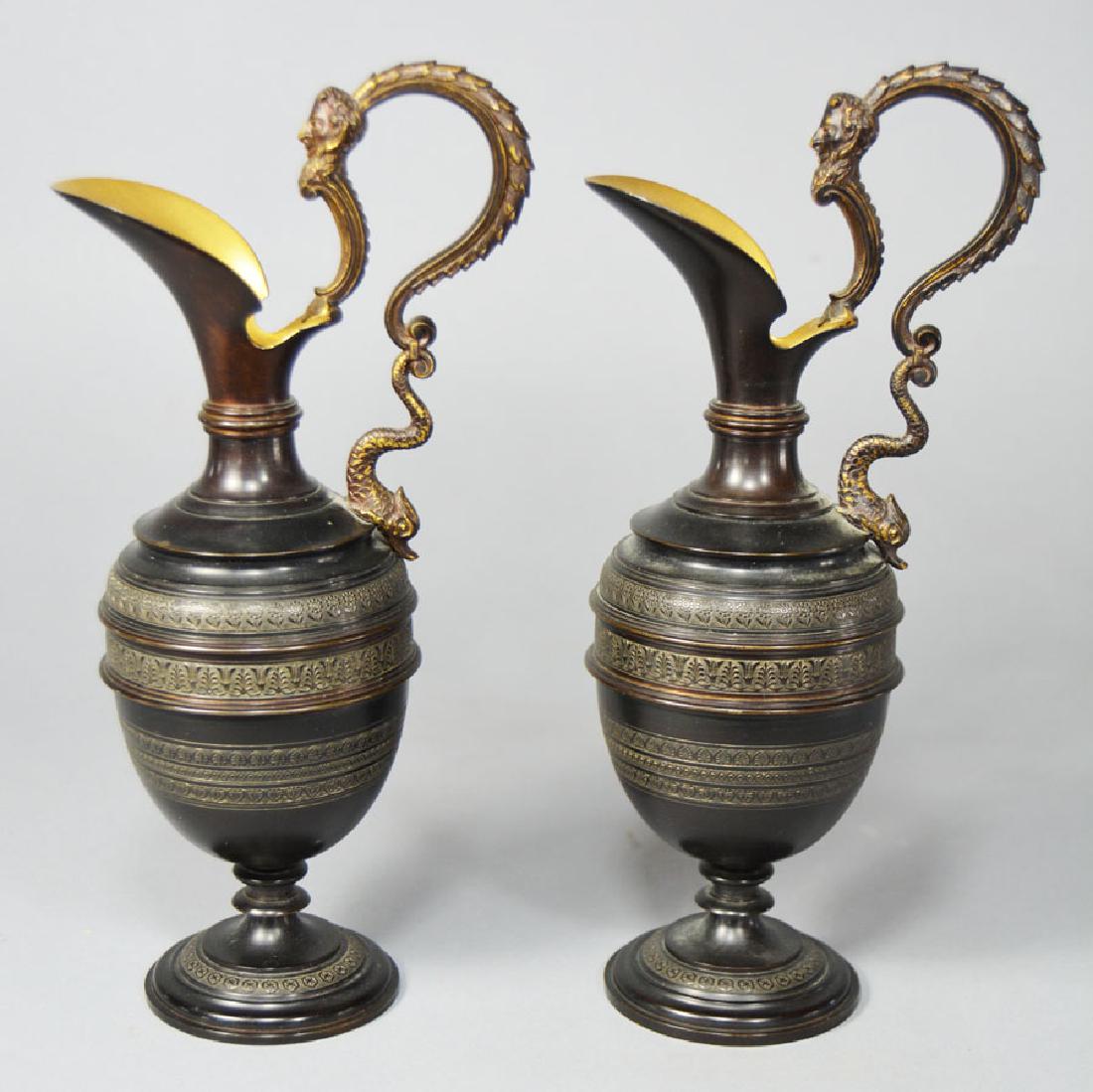Pair of Small Antique Bronze Urns: bulbous form, having a scrolling dolphin and mask decorated handle, gilt interior, footed, 9" high.
