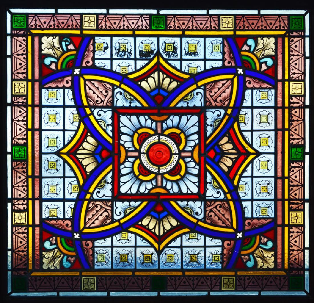 19th C. Archtectural Stained Glass Window: having a central circular raised bullseye surrounded by overall geometric patterns in blues, reds, greenss, yellow and orange, 40" wide, 38" high, in a wooden frame. Note: This window was removed some