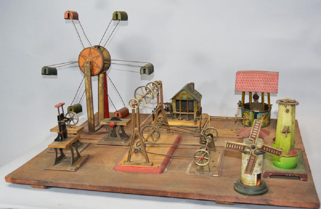 Early 20th C. Folk Art Tin Diorama of Miniature Belt: machines include a twin hammer, table saw, grinding wheel all marked Weeden, a windmill marked "Bavaria", a Jack and Jill well, a tall well with owl faces spigots, a building with water wheel and two