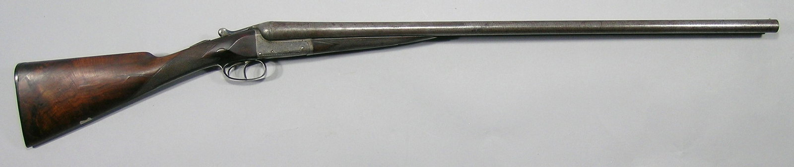 Early 20th C. English Side by Side Shotgun: 12-gauge, Damascus twist 30" barrels with British proof marks, scrolling engraving throughout frame, trigger guard and frame, figured walnut stock and forearm, serial #99104 on barrel and forearm only