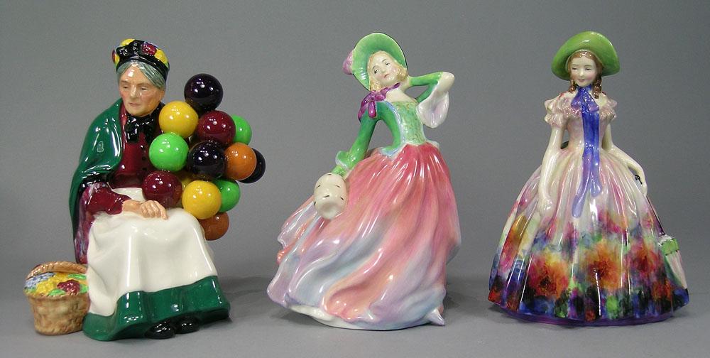 Three Royal Doulton Porcelain Figurines: comprising EASTER DAY 2099, 7 1/2" H., AUTUMN BREEZES 1911, 7 5/8" H. and THE OLD BALLOON SELLER 1315, 7 1/2" h.