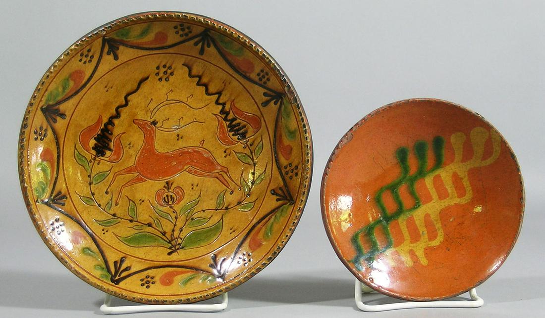 Two Contemporary Shooner Redware Pottery Shallow Bowls: comprising a small bowl with slip decoration, 5 7/8" dia., and a larger bowl with central incised stag decoration surrounded by a swag border, 8 3/8" dia.
