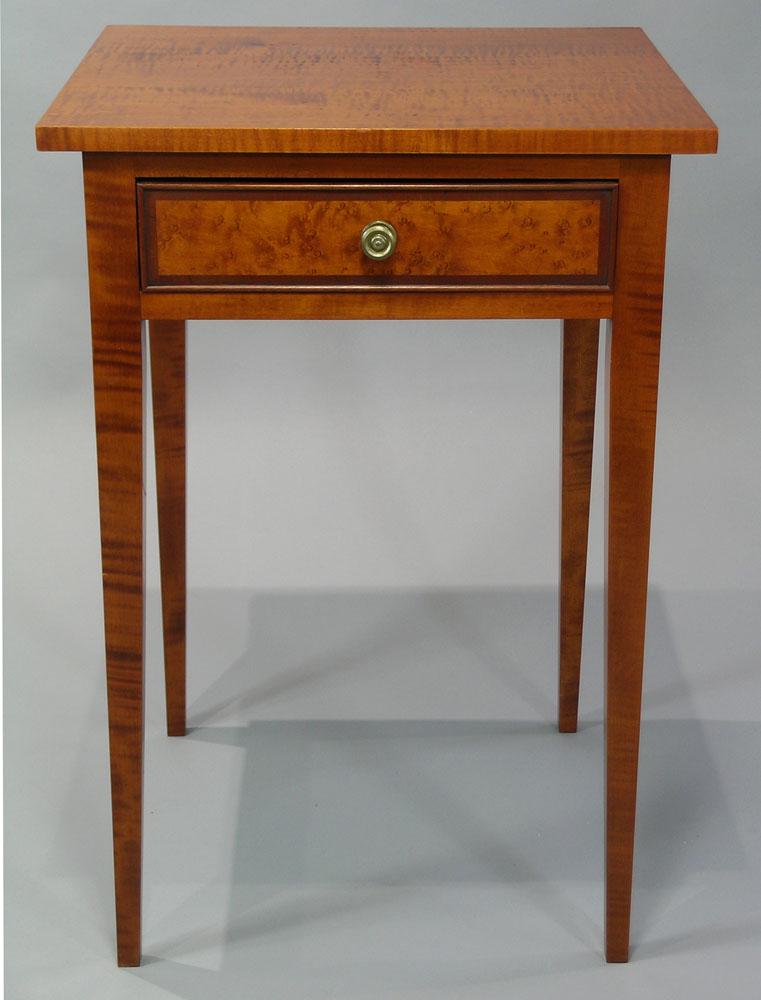 Eldred Wheeler Tiger Maple One Drawer Stand: Hepplewhite style, having a banded edge birdseye maple drawer front, raised on square tapering legs, 17 1/2" deep, 18 3/4" wide, 27 1/2" high. Note: Eldred Wheeler label on inside of drawer.