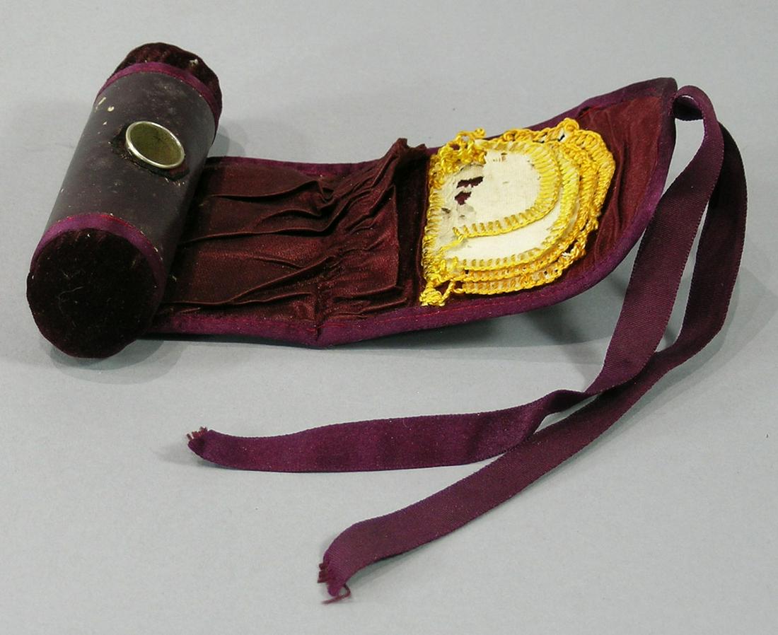Shaker Sewing Kit Roll: brown leather with purple velvet trim, fitted at each end with a velvet pin cushion, unrolling to show an interior pocket, four graduated needle holders and a metal thimble, held with satin ribbons, 5