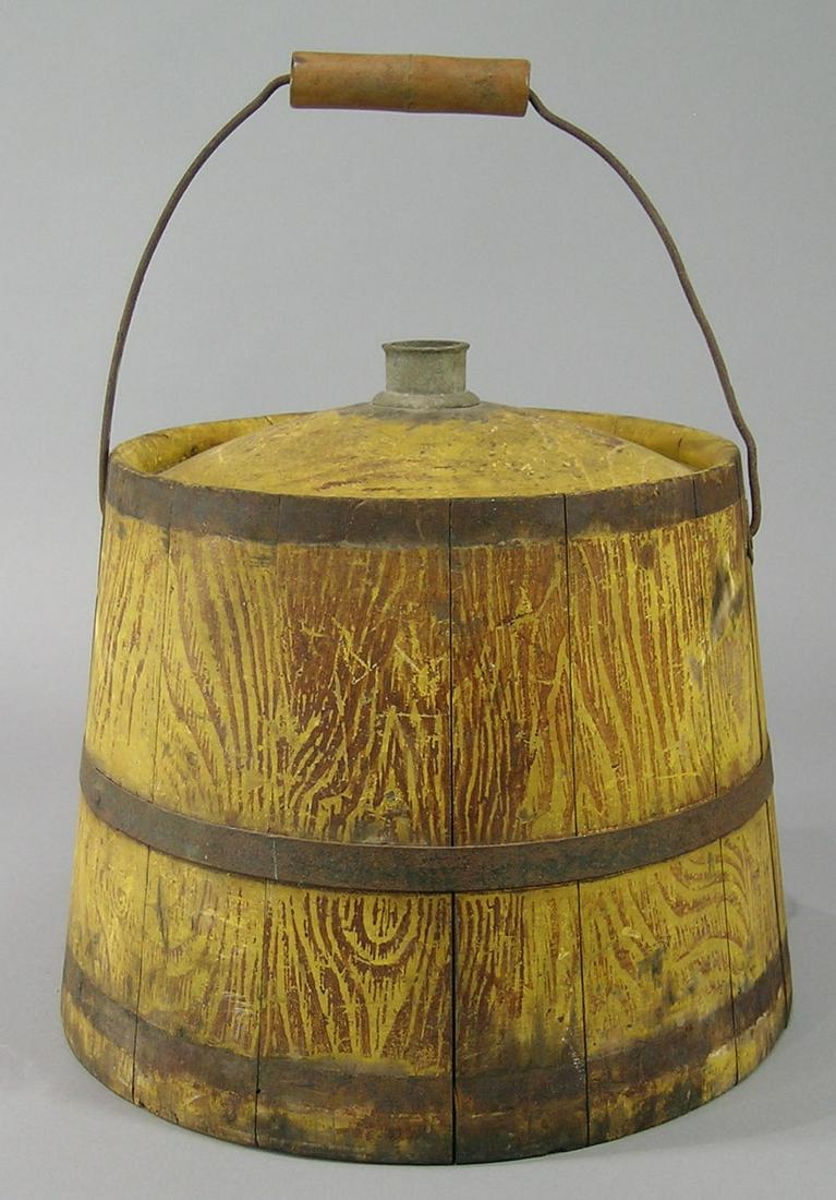 Shaker Made Grain Painted Kerosene Bucket: Second half-19th century. Stave constructed with three bands, having original grain patterned paint. Bale handle with tin diamond escutcheons, partially visible stenciled merchant label "Woodcock & Sa