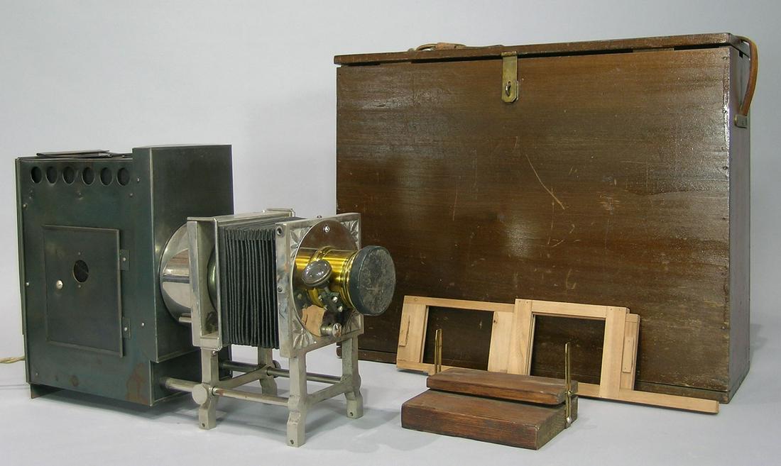 Herbert Spinneys' T.H. McAllister Magic Lantern: black tin light box behind a nickel plated adjustable frame, having the original wooden carrying box. Provenance: Came down through the family of Capt. Herbert McAllister to the present family member 