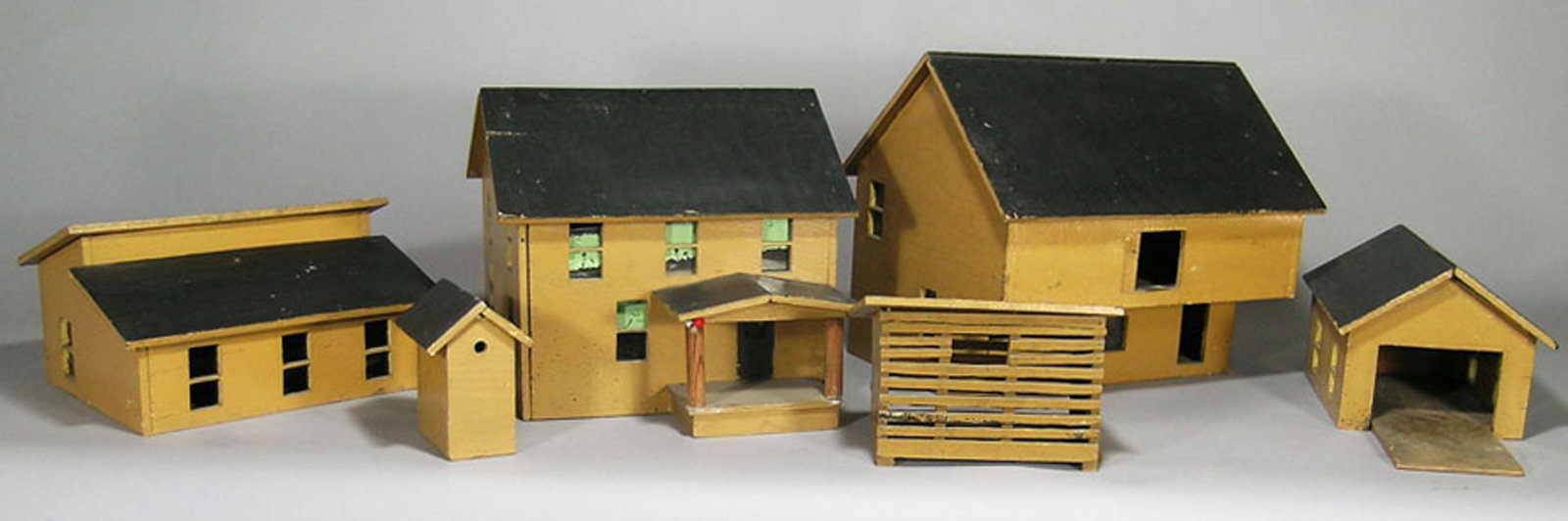 Seven Vintage Toy Farm Buildings: comprising a Dutch style barn, 13 1/2" long, 11 1/4" wide, 11 1/2" high, a house, two smaller barn buildings, a corn crib, a birdhouse, and a dog house that may not be original to the set. Accompanied