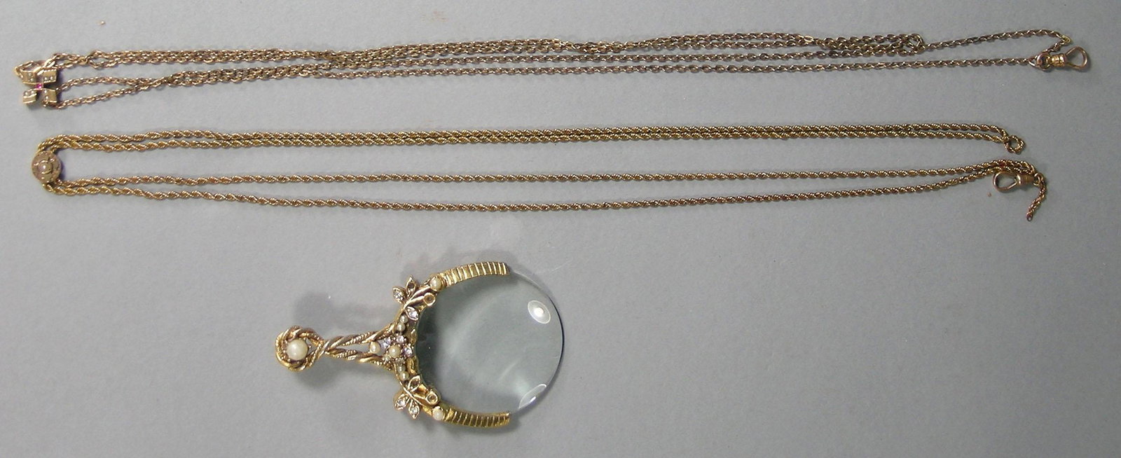 Three 10k Gold and Gold-Filled Items: comprising two gold-filled chains with 10K slides, and a gold filled magnifying glass