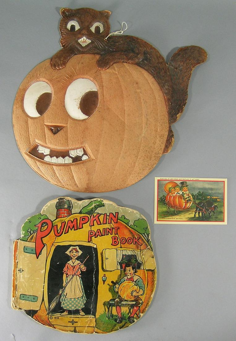 Two Vintage Halloween Ephemera Items: comprising a heavy paper relief Cat on a Pumpkin hanging decoration, and a Pumpkin Paint Book. Accompanying this lot is a replica relief postcard.