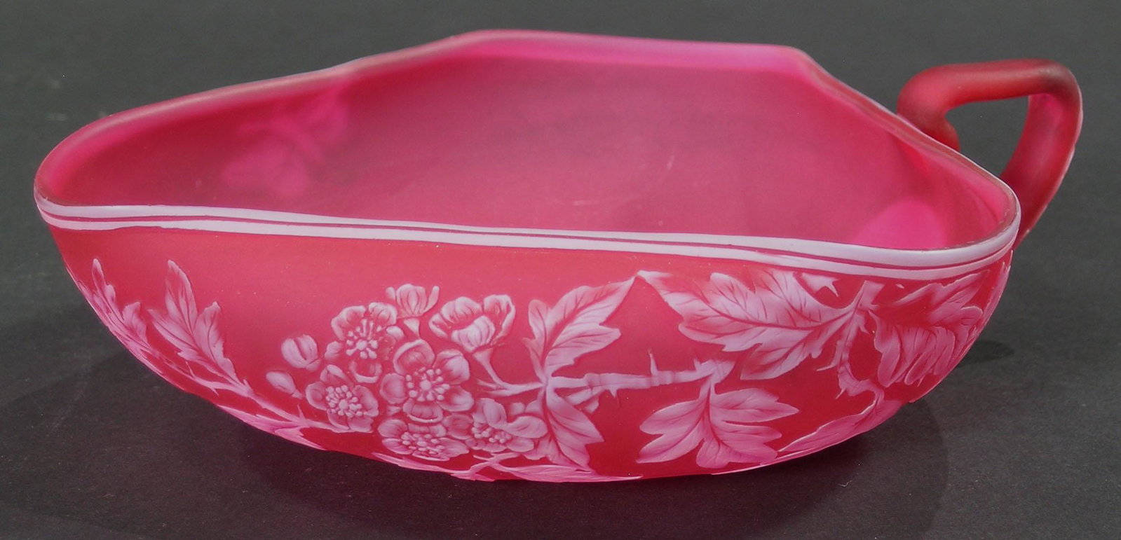 THOS. WEBB & SONS CAMEO GLASS NAPPYT: tri-corn shape with rolled rim, on one side having white cameo floral branch decoration, on the other side having a white cameo butterfly in flight, the handle having white cameo leaf decoration, 6 7/