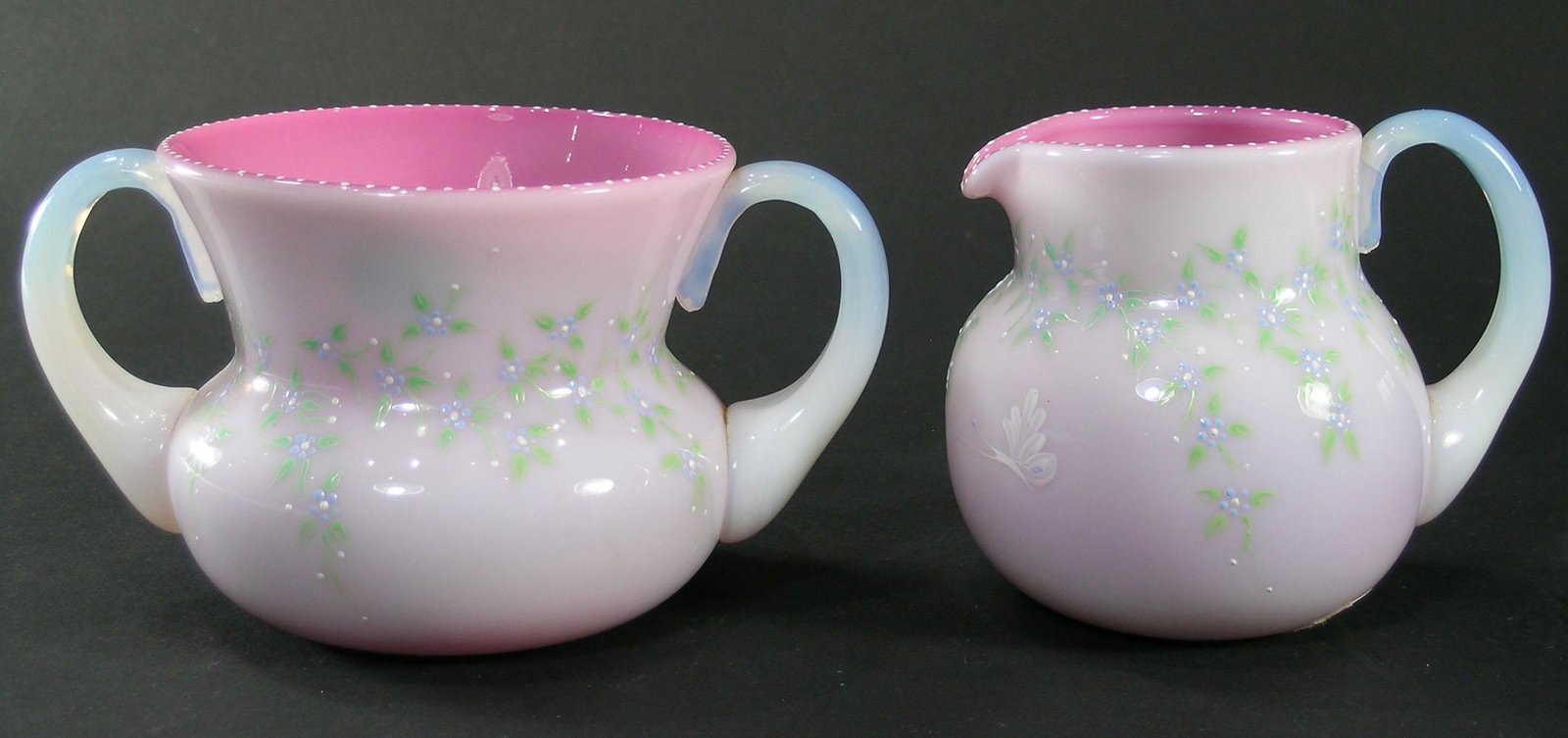 PAIRPOINT PEACHBLOW ENAMELED GLASS SUGAR BOWL AND: having enamel floral decoration and beaded rims, opalescent handles, both signed with an paper Pairpoint label on the underside, sugar bowl 3 1/4" high, creamer 3 1/2" high. NOTE: This set was formerl