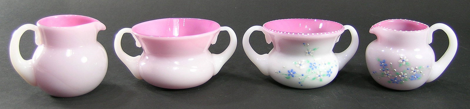 TWO SETS OF PAIRPOINT PEACHBLOW GLASS SUGAR BOWLS AND: one having enamel floral decoration, sugar bowl 2 1/8" high, creamer 2 1/4" high, remnants of what appears to be a blue diamond on the underside of the creamer, the other set undecorated, sugar bowl 2