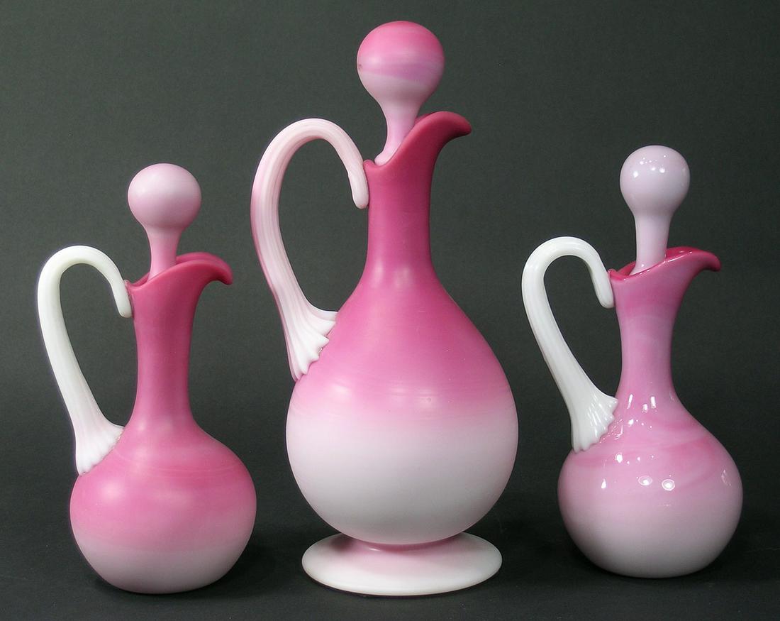 THREE PAIRPOINT PEACHBLOW GLASS CRUET BOTTLES: the large cruet, 10" high and one of the small cruets, 7 1/2" high having a matte finish, the other small cruet, 7 1/2" high having a glossy finish, all having ground pontils. Provenance: All formerly