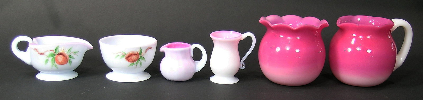 SIX BURMESE GLASS TABLE ARTICLES: all having gloss finish, comprising two matching sugar bowls and creamers, one having ruffled rims and being approx. 4" high,, and one set having a leaf form creamer and both having hand painted decor