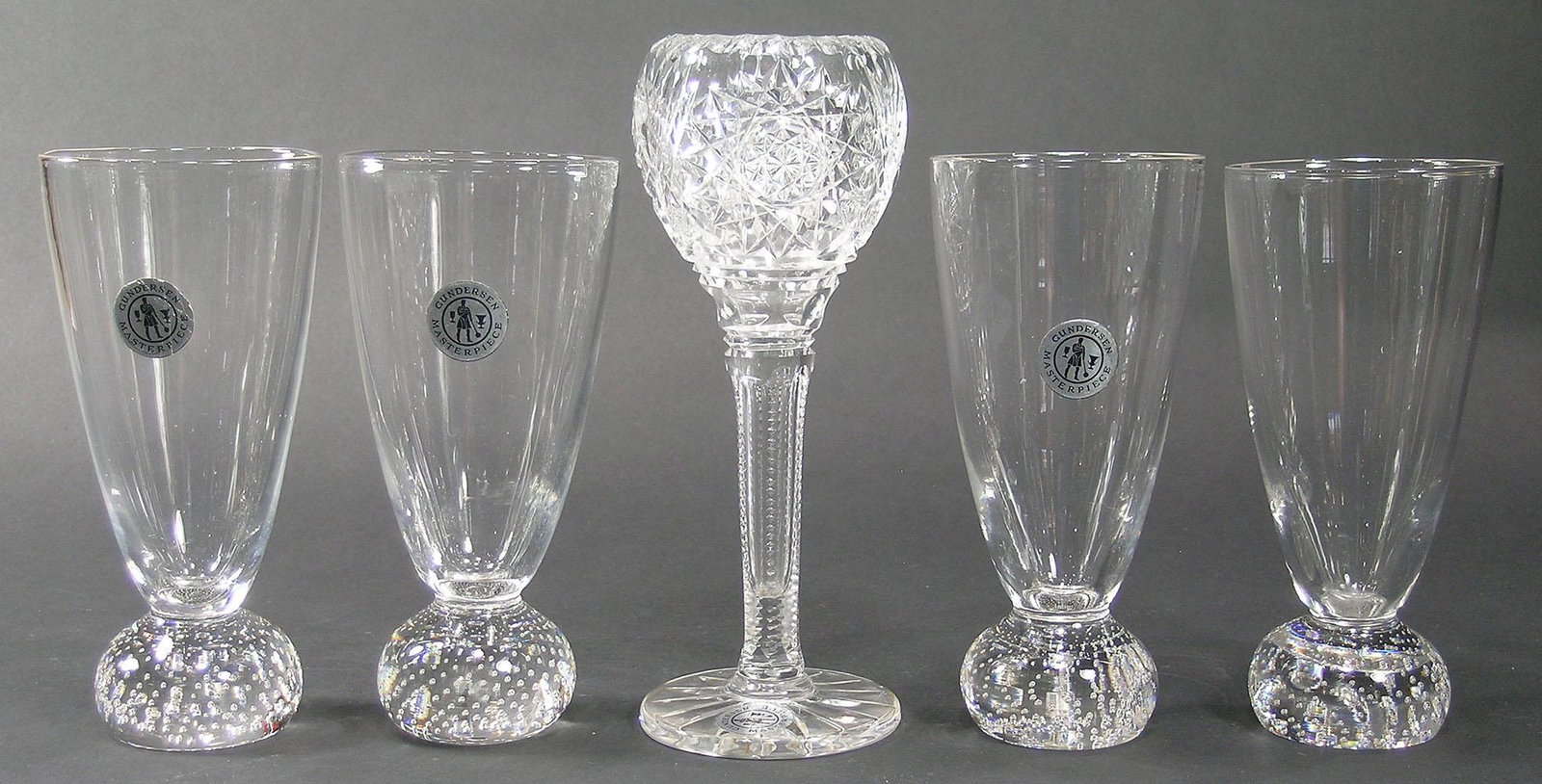 FIVE GUNDERSEN MASTERPIECE GLASS DRINKING VESSELS: colorless glass, comprising a cut glass wine glass, Hobstar and fan pattern, 8" high, and four water glasses having a ball base with controlled air bubbles and polished pontils, 6 1/2" high, all havin