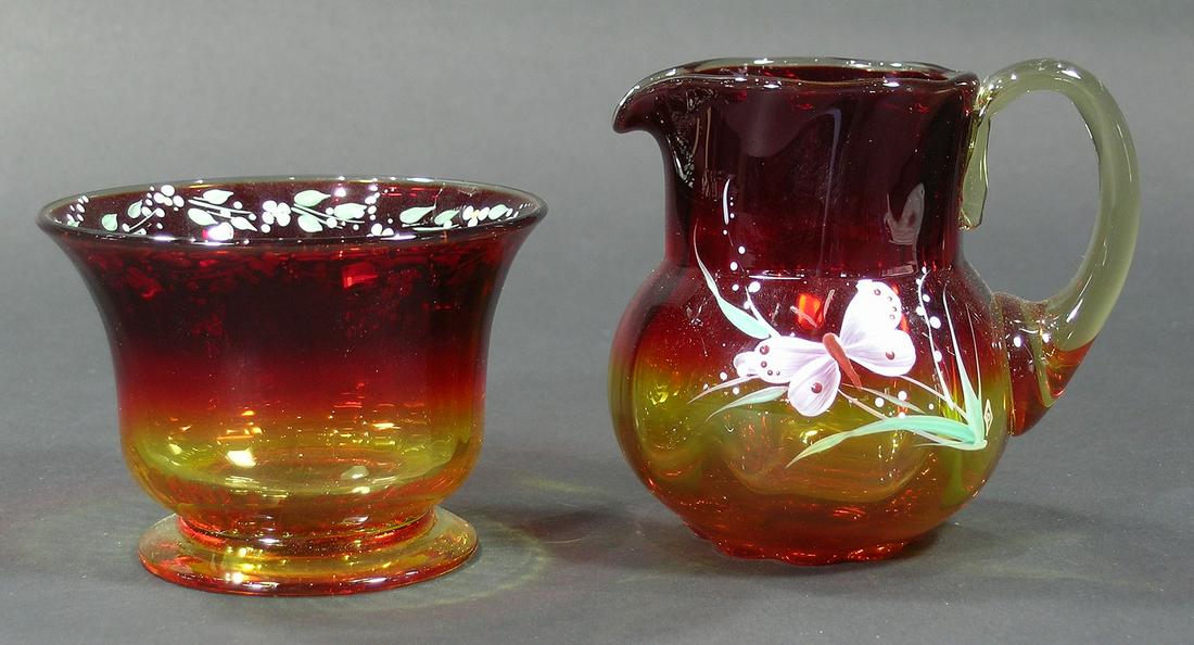PAIRPOINT AMBERINA GLASS SUGAR BOWL AND CREAMER: ribbed optic, both having hand painted enamel decoration, the sugar bowl with floral and leaf decoration, 3 1/2" dia., 2 1/2" high, and the sugar bowl with butterfly, floral and leaf decoration, unfin