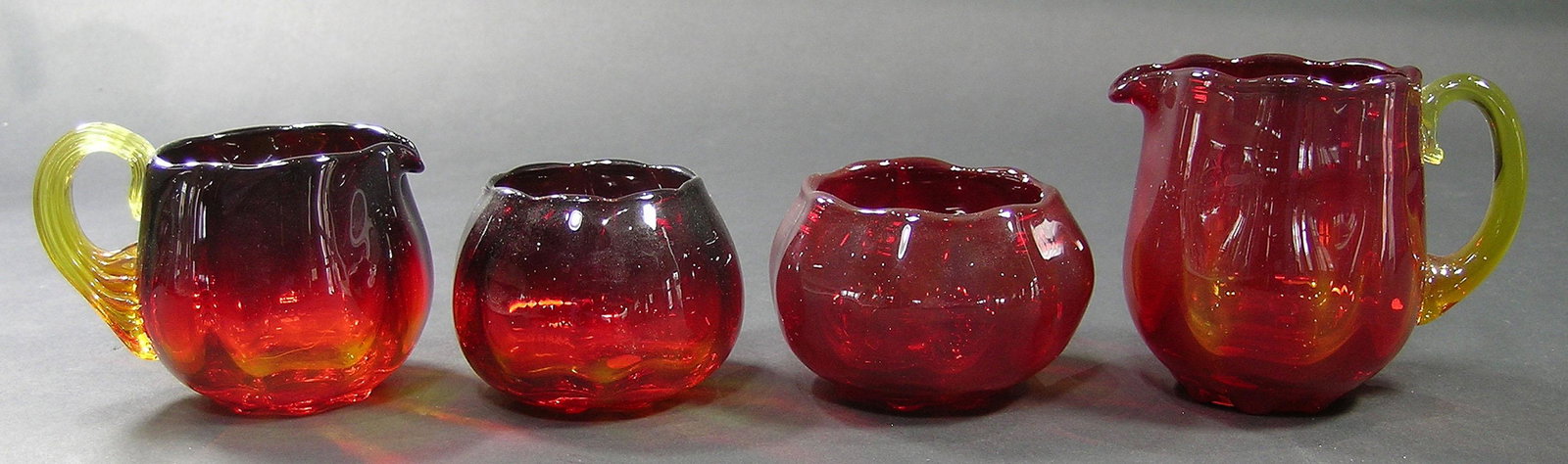 TWO SETS PAIRPOINT AMBERINA GLASS SUGAR BOWLS AND: all ribbed optic, one creamer having a ribbed handle, the largest creamer being 3 1/2" high, unfinished pontils