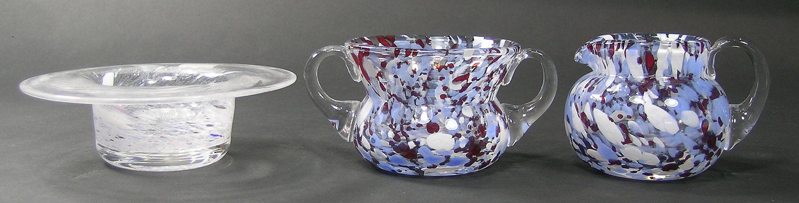 THREE PAIRPOINT GLASS TABLE ARTICLES: comprising a sugar bowl and creamer having internal ruby, light blue and white swirl decoration, both having colorless glass handles, sugar bowl 3 3/4" dia., 2 3/4" high, and a candy dish having a fla