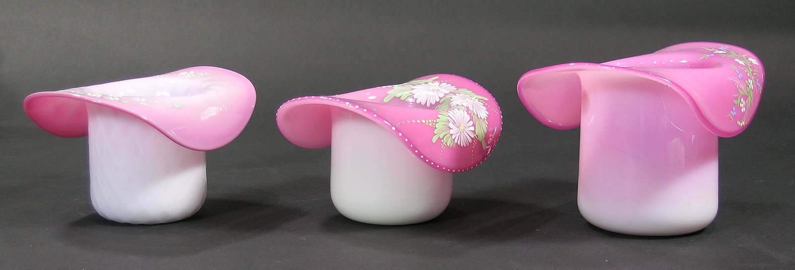 THREE PAIRPOINT PEACHBLOW GLASS HATS: various sizes, all having hand painted enamel floral and leaf decoration, one with quilted body, the largest being 3 1/2" high