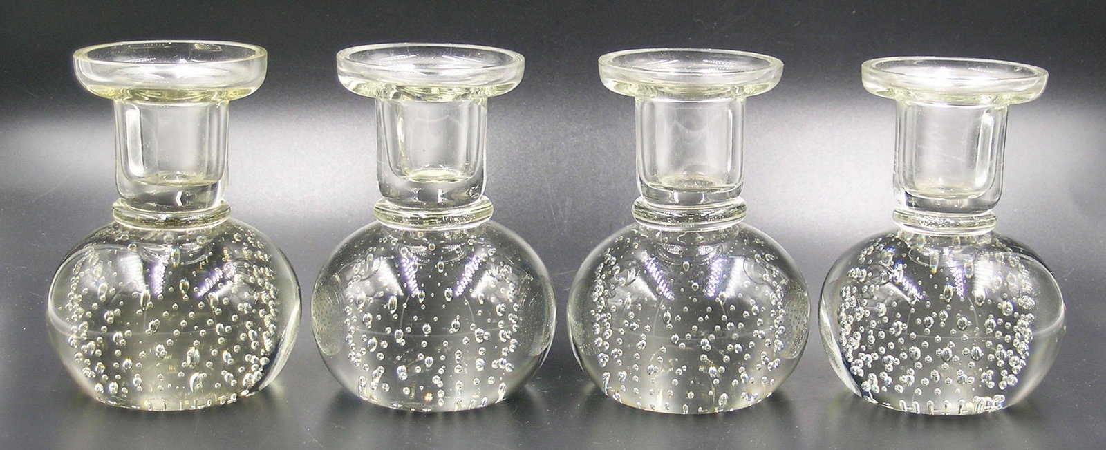 FOUR PAIRPOINT GLASS CANDLESTICKS: colorless glass, two pairs, all having bases with controlled air bubbles, 3 5/8" high