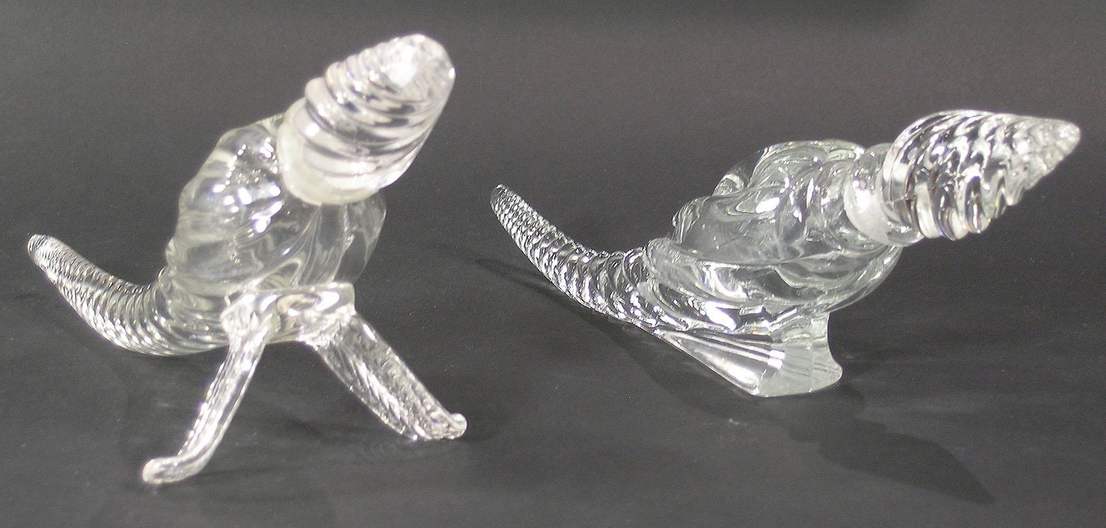 TWO PAIRPOINT GLASS CORNUCOPIA PERFUME BOTTLES: colorless glass, both having spiral twist stoppers, one raised on leaf form legs, the other on a tapering block support, both approx. 10 1/2" long