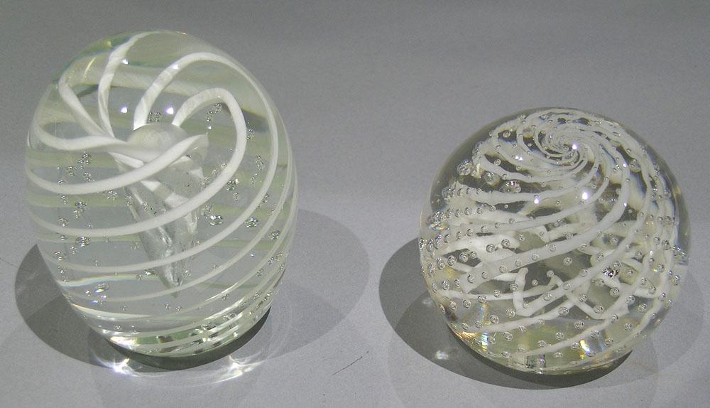 TWO PAIRPOINT ART GLASS PAPERWEIGHTS: both having white swirl pattern and entrapped air bubbles, one having a central tear drop air bubble, the other having a white star inside the swirl pattern and has a paper label, the largest being 3"
