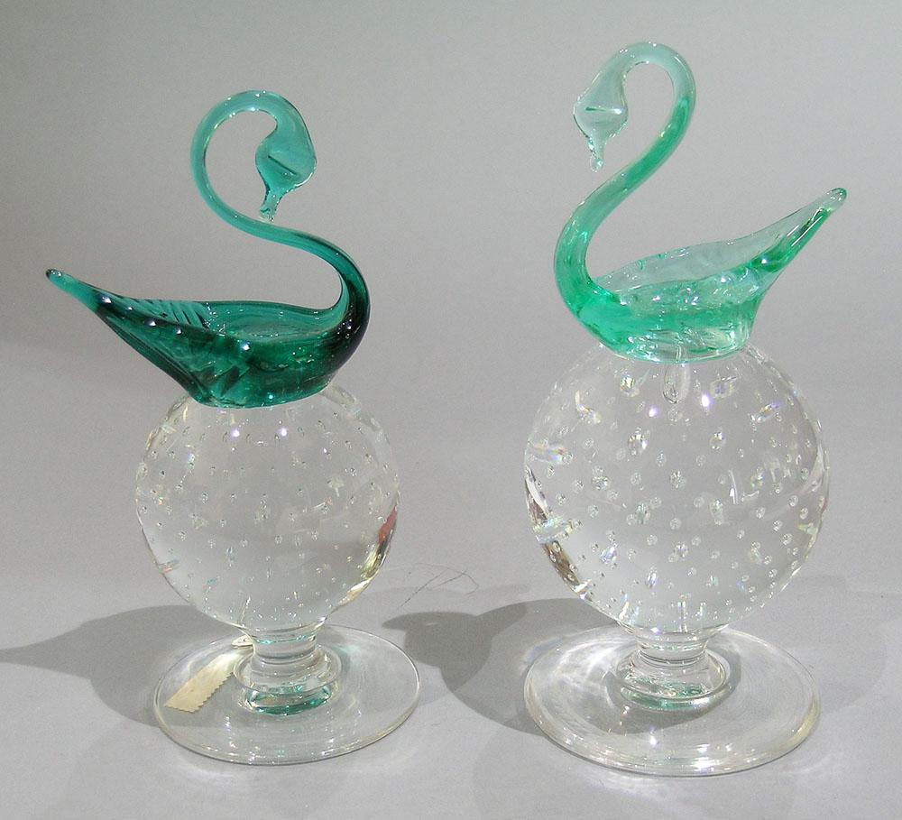 TWO PAIRPOINT ART GLASS PEDESTAL PAPERWEIGHTS WITH: both having a colorless glass ball with entrapped air bubbles, one having an light aqua glass swan, 6 1/2" high, and one with a dark aqua glass swan having etched wreath on underside of base and havin
