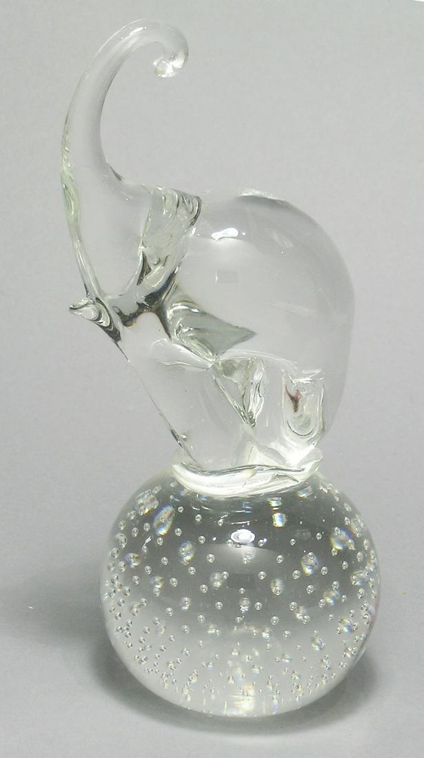 GUNDERSEN PAIRPOINT ART GLASS ELEPHANT PAPERWEIGHT: colorless glass, having a standing elephant with raised trunk on a ball base having entrapped air bubbles, 8" high