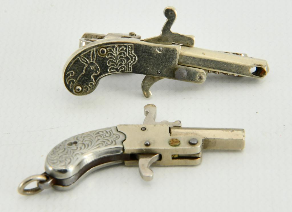 (2) Vtg Miniature Pinfire Pistol Austria Cap Gun: lot contains (2) Vintage Miniature Pinfire Pistol Austria Cap Gun Toy Gun Miniature Pistol OR GUN Fob berloque. One comes with Tie clasp attached, the firing hole is out the sides of the barrel, refer