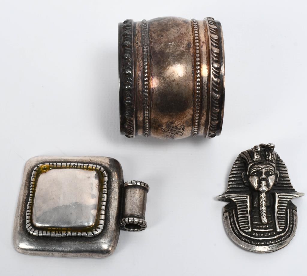 Silver Napkin Holder, 2 Silver Necklace pend 96gra: Discover the elegance of silver with this collection featuring a Sterling Silver Napkin Ring engraved with B487 on the inside, a Square-Shaped Silver Necklace Pendant, and a Silver Egyptian Head Penda