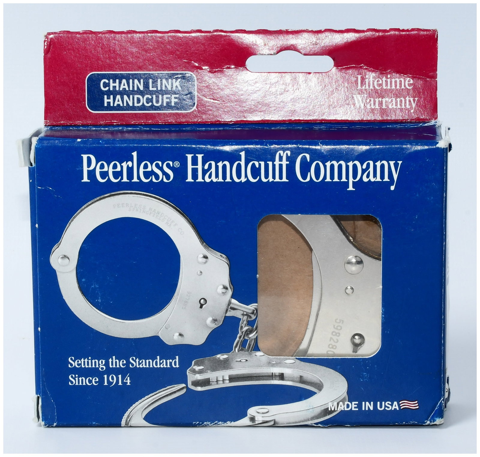 A Pair of Peerless Handcuff Company Model 700C Chain Link Handcuffs, New in Original Packaging: A pair of Peerless Handcuff Company Model 700C Chain Link Handcuffs. Crafted from polished, silver-toned metal, likely steel, each cuff is marked "PEERLESS HANDCUFF CO. SPRINGFIELD, MA", "PATENTED", "