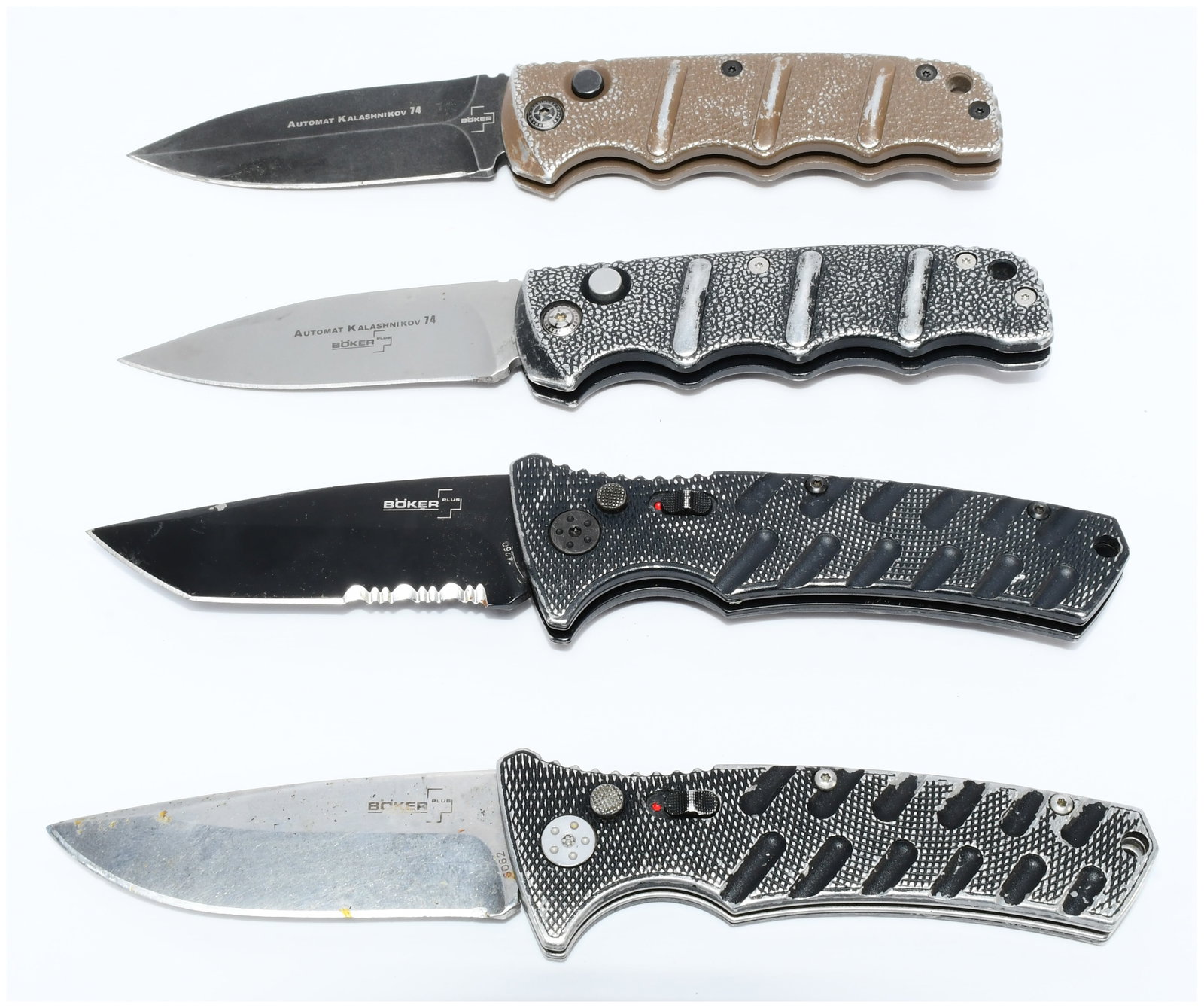Four Boker Strike Automatic Folding Knives: A group of four Boker Strike automatic folding knives, all products of the German manufacturer Boker. Two knives bear the inscription "AUTOMAT KALASHNIKOV 74" alongside the "BOKER" logo on their blade